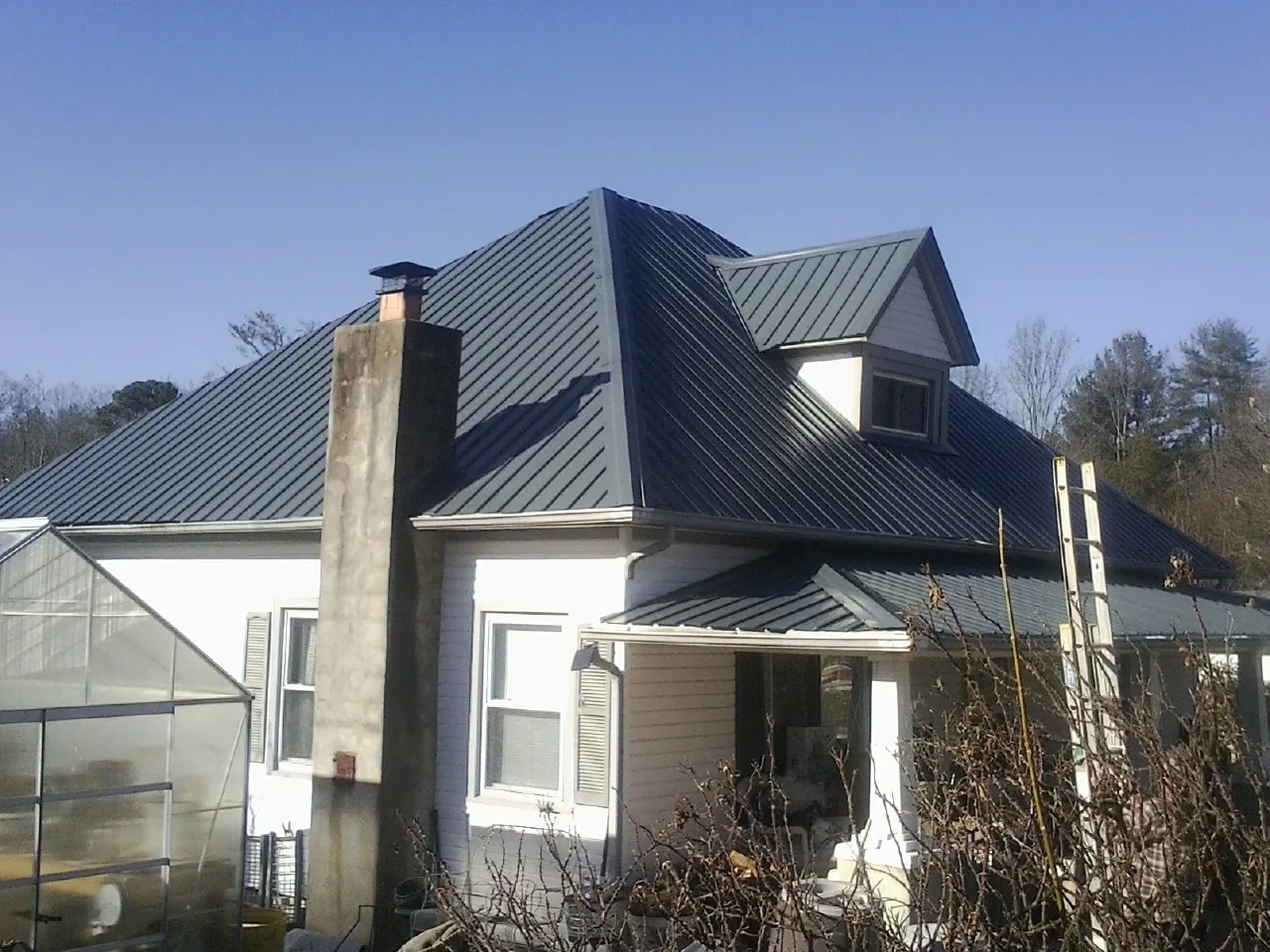 Dark blue standing seam metal roof on a white farmhouse with dormer — Slate & Tile Roof Repair by Roofing Brothers in Sabinsville