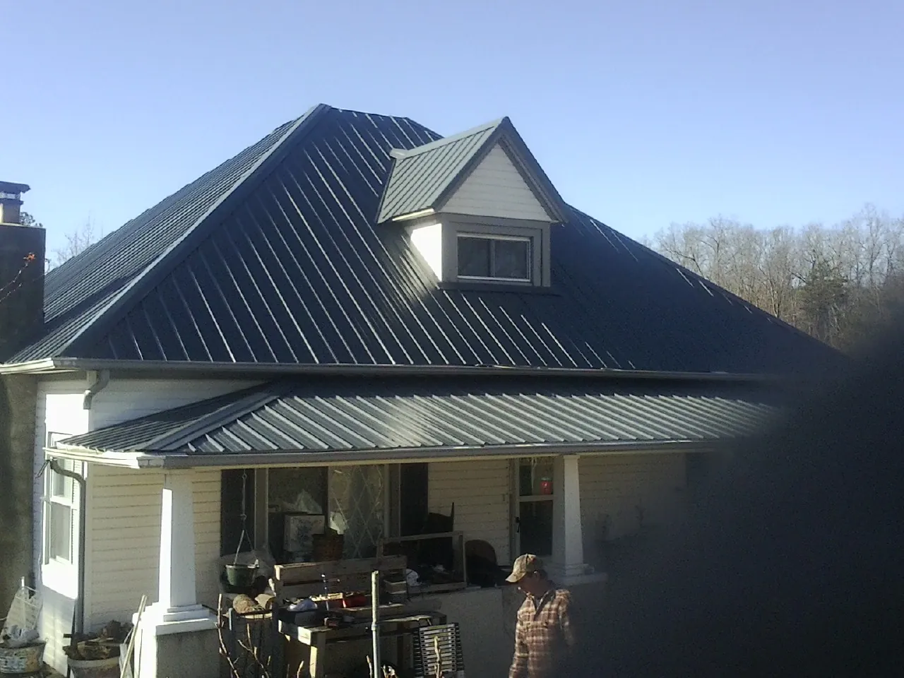 Dark blue standing seam metal roof with a dormer above a front porch in Sabinsville