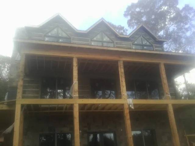 Dormers and porch framing on a large log home under construction — Roof Coating work by our crew in Sabinsville