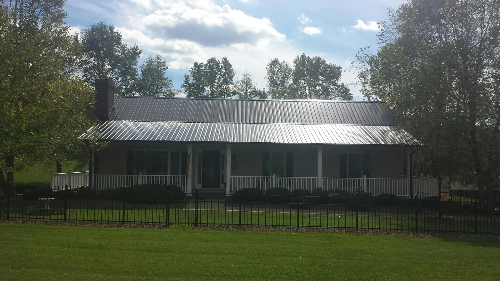 Gray metal roof on a brick ranch with a full width front porch — Gutter Guard Installation work by our crew in Sabinsville