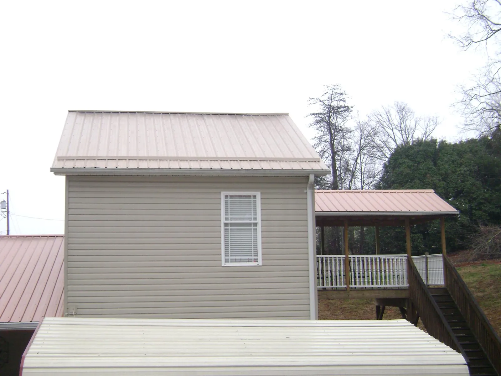 Tan metal roofs on a two story addition and attached porch, from a Roof Replacement job in Sabinsville