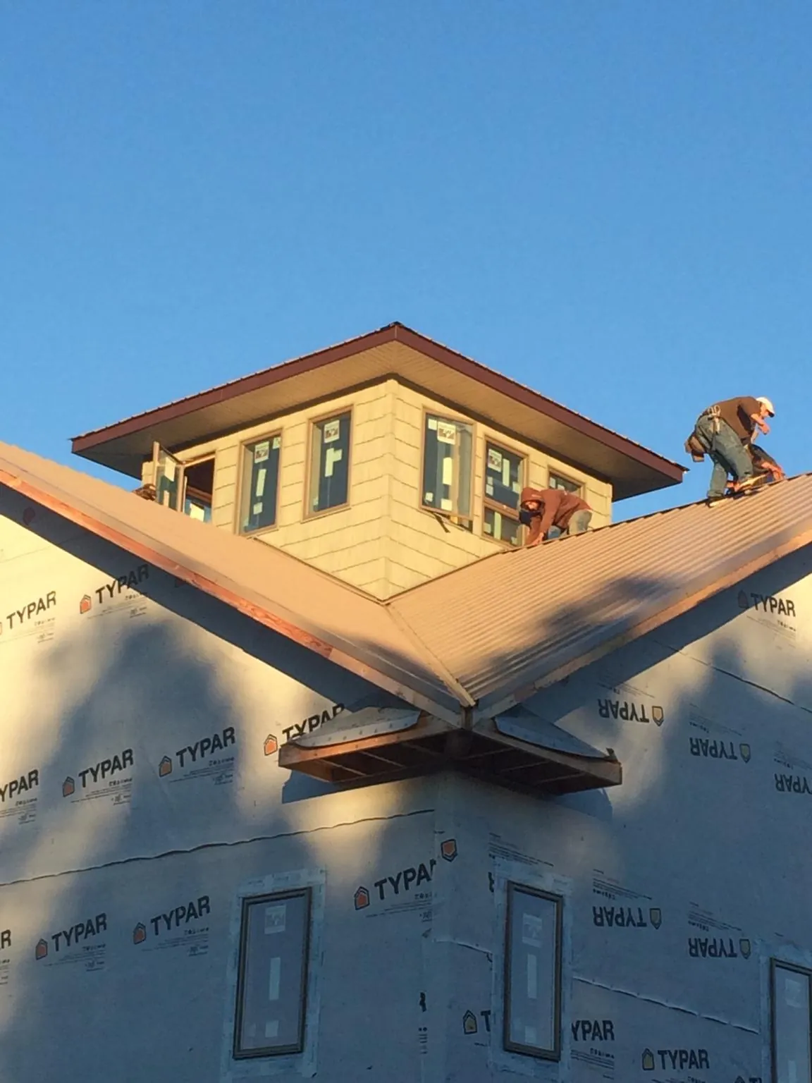 Roofers working around a rooftop cupola on a new metal roof at sunset — Roof Waterproofing in Sabinsville by Roofing Brothers